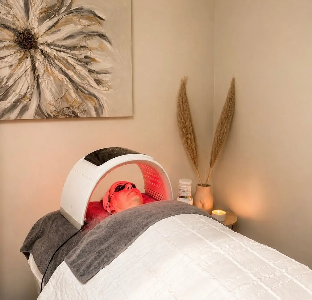 A client relaxing under LED light therapy at Pause by Mel